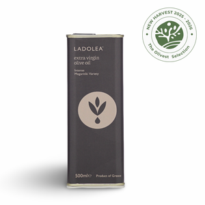 A tall, slim black metal tin of Ladolea extra virgin olive oil, featuring a beige circular logo and text. It is displayed on a clean white background with a soft shadow, alongside a green and white 'New Harvest 2025 - 2026 The Olivate Selection' badge in the upper right corner.