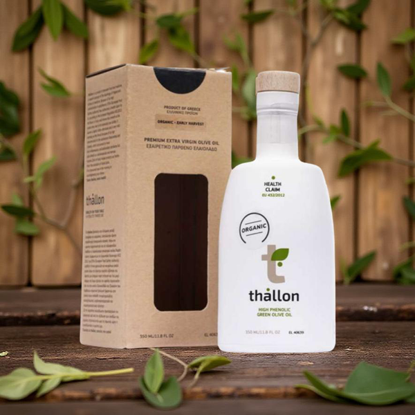 Thallon olive oil bottle and packaging on a wooden surface with green leaves in the background
