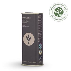 A 500ml can of L'ADOLEA extra virgin olive oil, Madrigalide Variet, with a dark gray label and gold accents, shown on a white background with a green 'New Harvest 2025-2026 The Olivest Selection' seal in the top right corner.